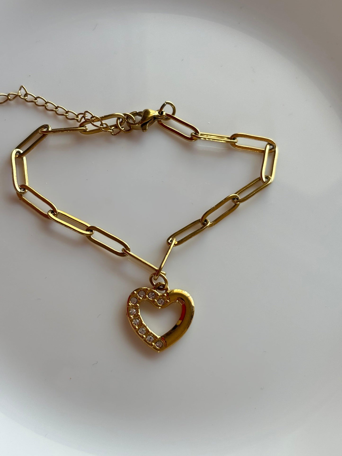 Charming heart-linked bracelet with a gold chain and a heart pendant adorned with rhinestones.