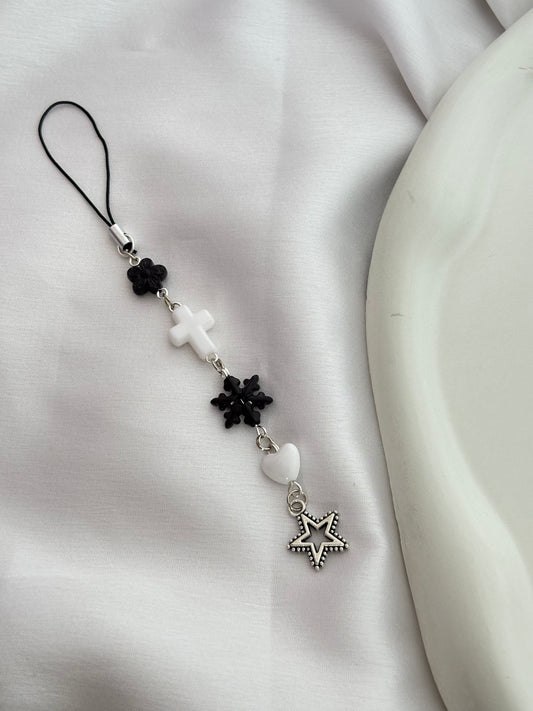 Phone charm with star and flower designs on a white fabric background