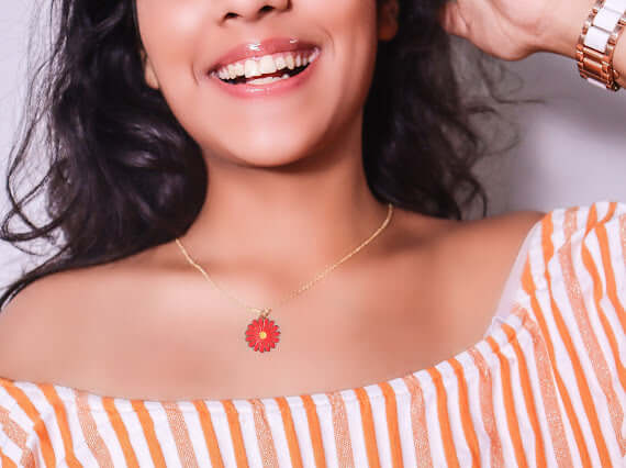 Woman wearing Red Daisy Necklace made of tarnish-resistant stainless steel, adding a vibrant pop of color to her striped outfit.