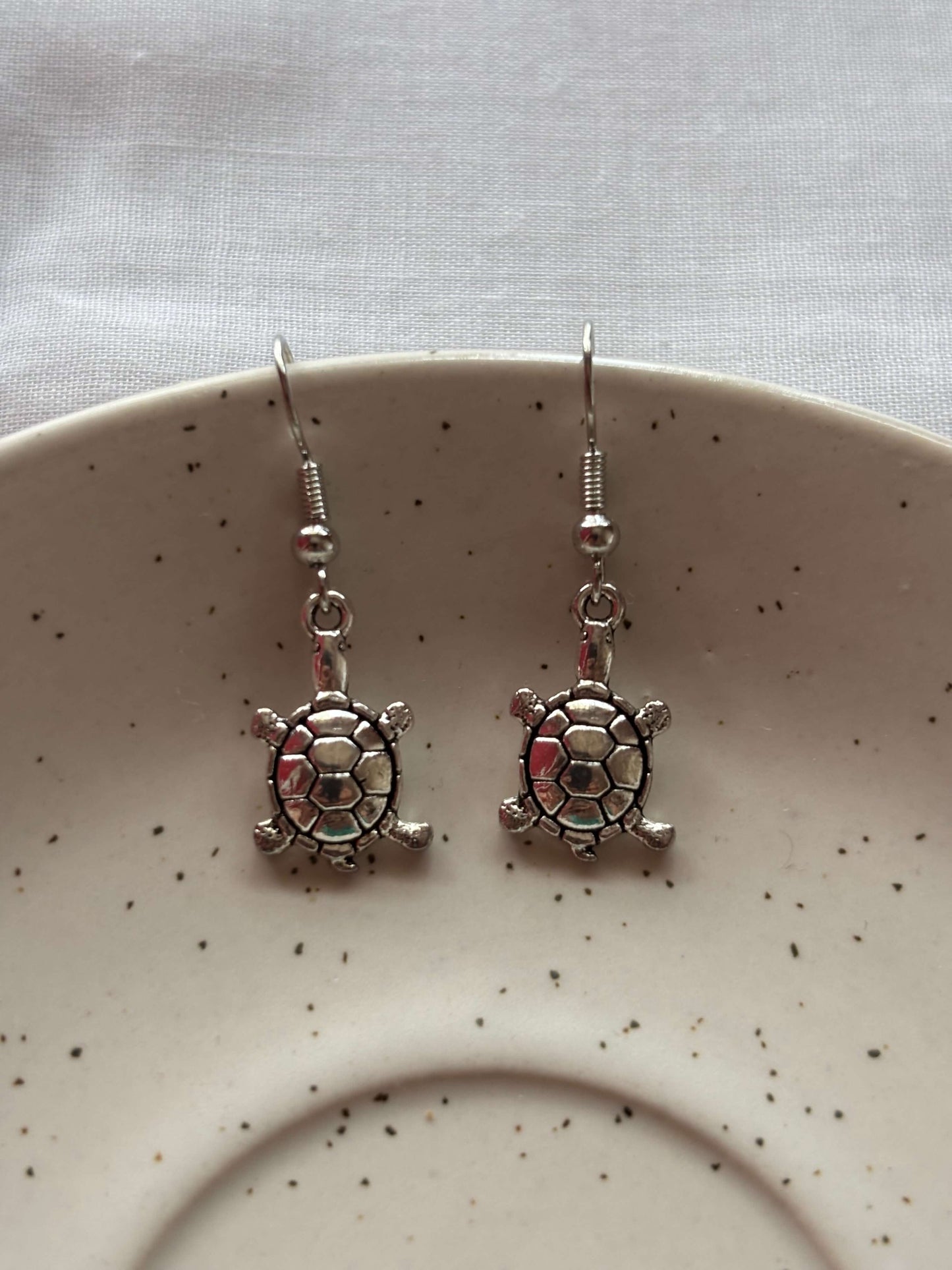 Elegant brass tortoise earrings on neutral-toned pottery plate for a sophisticated look